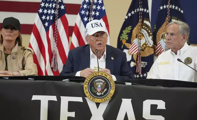 President Donald Trump speaks as first lady Melania Trump, left, and Texas Gov. Greg Abbott listen during a roundtable discussion with first responders and local officials at Hill Country Youth Event Center in Kerrville, Texas, during a tour to observe flood damage, Friday, July 11, 2025. (AP Photo/Jacquelyn Martin)
