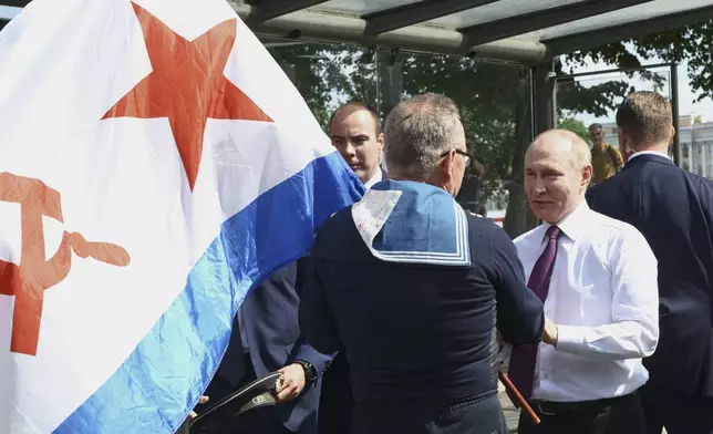 Russian President Vladimir Putin, right, congratulates a naval veteran holding a Soviet Nay flag, on Navy Day in St. Petersburg, Russia, on Sunday, July 27, 2025. (Alexei Danichev, Sputnik, Kremlin Pool Photo via AP)