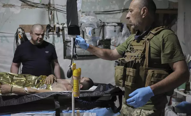 In this photo provided by Ukraine's 24th Mechanized Brigade press service, military medics give first aid to a wounded Ukrainian soldier at a medical stabilisation point in Donetsk region, Ukraine, Friday, July 25, 2025, (Oleg Petrasiuk/Ukraine's 24th Mechanized Brigade via AP)