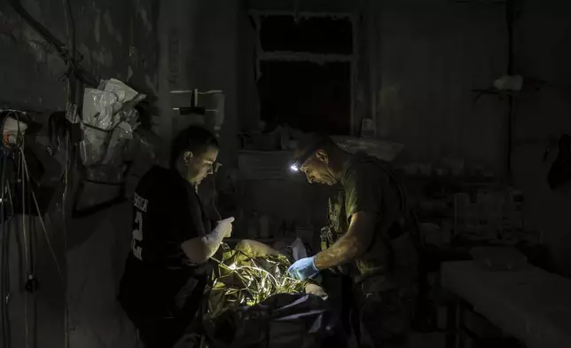 In this photo provided by Ukraine's 24th Mechanized Brigade press service, military medics give first aid to a wounded Ukrainian soldier at a medical stabilisation point in Donetsk region, Ukraine, Friday, July 25, 2025, (Oleg Petrasiuk/Ukraine's 24th Mechanized Brigade via AP)