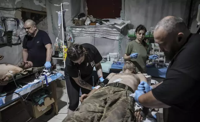 In this photo provided by Ukraine's 24th Mechanized Brigade press service, military medics give first aid to a wounded Ukrainian soldiers at a medical stabilisation point in Donetsk region, Ukraine, Friday, July 25, 2025, (Oleg Petrasiuk/Ukraine's 24th Mechanized Brigade via AP)