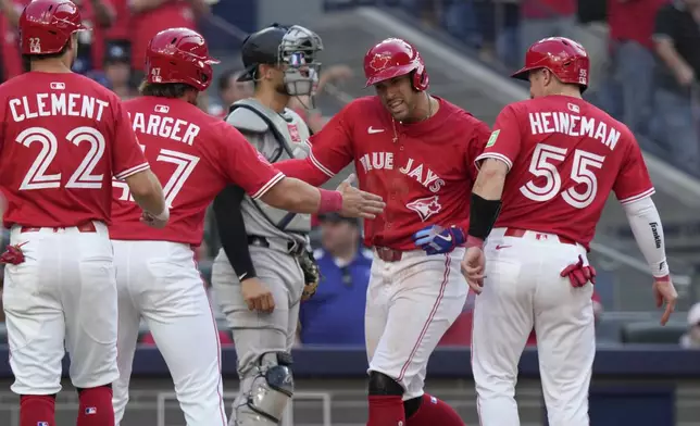 Toronto Blue Jays' George Springer (4) celebrates with teammates after hitting a grand slam off of New York Yankees pitcher Luke Weaver during the seventh inning of a baseball game in Toronto on Tuesday, July 1, 2025. (Frank Gunn/The Canadian Press via AP)