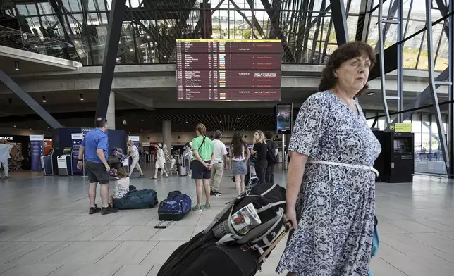Passengers look a departures information board at Saint-Exupery airport, near Lyon, as French air traffic controllers launched a two-day strike to demand better working conditions, Friday, July 4, 2025. (AP Photo/Laurent Cipriani)