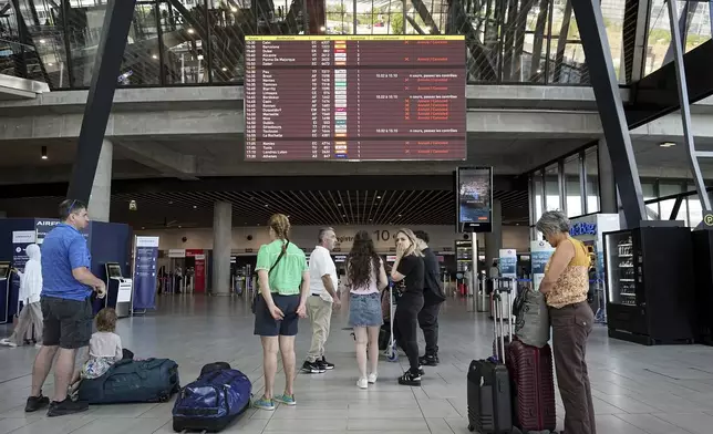 Passengers look a departures information board at Saint-Exupery airport, near Lyon, as French air traffic controllers launched a two-day strike to demand better working conditions, Friday, July 4, 2025. (AP Photo/Laurent Cipriani)