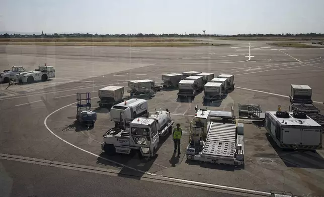 A worker walks on the tarmac at the Saint-Exupery airport, near Lyon, France, as French air traffic controllers launched a two-day strike to demand better working conditions, Friday, July 4, 2025. (AP Photo/Laurent Cipriani)