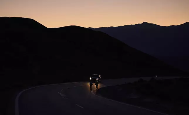Danny Westergaard, left, competes with pacing help from daughter Madison Westergaard as the sun rises during the Badwater 135 Ultramarathon, Tuesday, July 8, 2025, in Death Valley National Park, Calif. (AP Photo/John Locher)