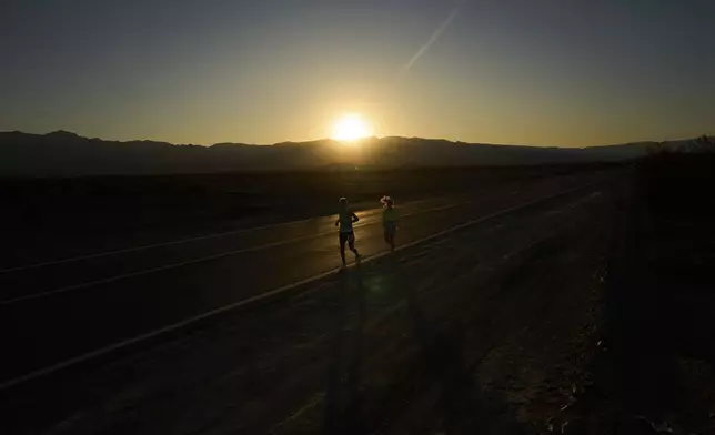 Danny Westergaard, left, runs with pacing help from daughter Madison Westergaard as the sun rises during the Badwater 135 Ultramarathon, Tuesday, July 8, 2025, in Death Valley National Park, Calif. (AP Photo/John Locher)
