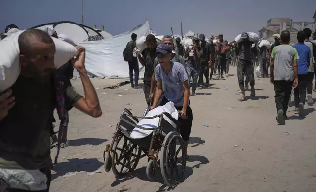 Palestinians carry sacks of flour unloaded from a humanitarian aid convoy that reached Gaza City from the northern Gaza Strip, Sunday, July 27, 2025. (AP Photo/Abdel Kareem Hana)