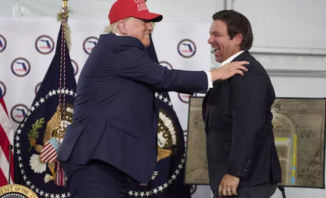 President Donald Trump talks with Gov. Ron DeSantis, R-Fla., during a roundtable at "Alligator Alcatraz," a new migrant detention facility at Dade-Collier Training and Transition facility, Tuesday, July 1, 2025, in Ochopee, Fla. (AP Photo/Evan Vucci)