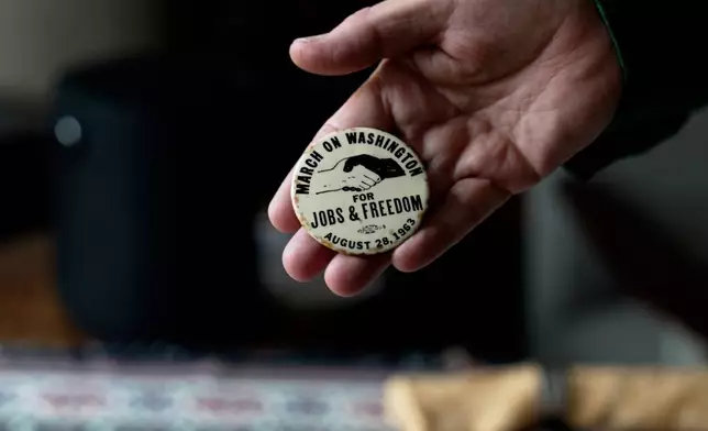 In this still image taken from video, a button from the March on Washington for Jobs an Freedom is held by Walter Naegle, Bayard Rustin's partner and a consultant on projects related to his life and work, on Saturday, June 28, 2025, in New York (AP Photo/Mary Conlon)