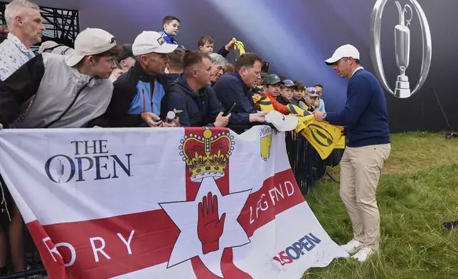 Rory McIlroy of Northern Ireland signs autographs on the 18th green following a practice round for the 2025 British Open golf championship at the Royal Portrush Golf Club, Northern Ireland, Monday, July 14, 2025. (AP Photo/Peter Morrison)