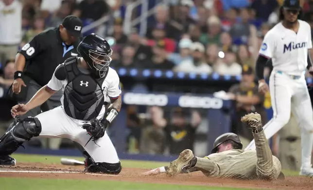 San Diego Padres' Jackson Merrill slides in to home past Miami Marlins catcher Agustín Ramírez to score on a double by San Diego Padres Martín Maldonado, in the second inning of a baseball game, Monday, July 21, 2025, in Miami. (AP Photo/Rebecca Blackwell)