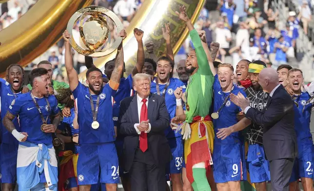 Chelsea's Reece James (24) lifts the trophy as President Donald Trump looks on following the Club World Cup final soccer match between Chelsea and PSG in East Rutherford, N.J., Sunday, July 13, 2025. (AP Photo/Seth Wenig)
