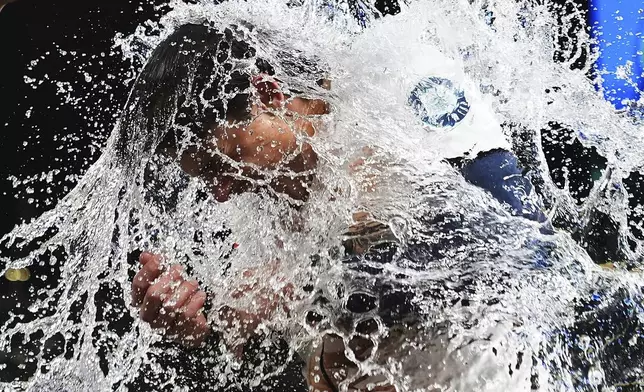 Seattle Mariners' Cole Young is doused by teammate J.P. Crawford after hitting a game-winning single against the Houston Astros during the 11th inning of a baseball game Saturday, July 19, 2025, in Seattle. (AP Photo/Lindsey Wasson)