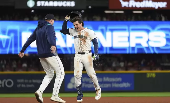 Seattle Mariners' Cole Young, facing, celebrates hitting a game-winning single against the Houston Astros in the 11th inning of a baseball game Saturday, July 19, 2025, in Seattle. (AP Photo/Lindsey Wasson)