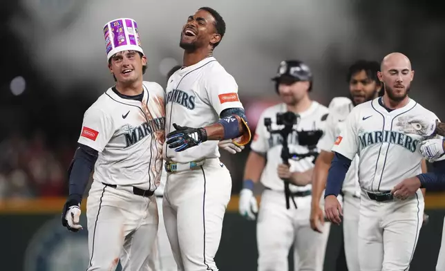 Seattle Mariners' Cole Young, left, celebrates with Julio Rodriguez, second from left, after hitting a game-winning single against the Houston Astros in the 11th inning of a baseball game Saturday, July 19, 2025, in Seattle. (AP Photo/Lindsey Wasson)