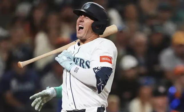 Seattle Mariners' Dylan Moore reacts after hitting an RBI groundout off the end of his bat to score Cal Raleigh against the Houston Astros during the 10th inning of a baseball game Saturday, July 19, 2025, in Seattle. (AP Photo/Lindsey Wasson)