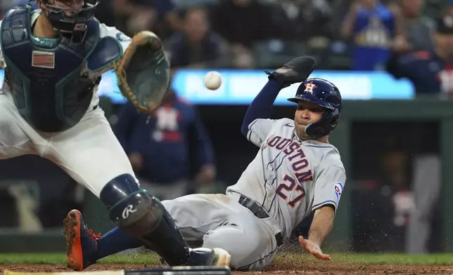 Houston Astros' Jose Altuve slides into home to score on an RBI single from Christian Walker ahead of the tag from Seattle Mariners catcher Cal Raleigh, left, during the sixth inning of a baseball game Saturday, July 19, 2025, in Seattle. (AP Photo/Lindsey Wasson)