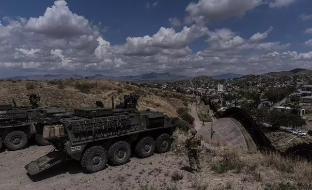 U.S. Army Sgt. Salvador Hernandez stands beside Stryker combat vehicles while watching over the U.S.-Mexico border fence from a hilltop in Nogales, Ariz., Tuesday, July 22, 2025. (AP Photo/Jae C. Hong)