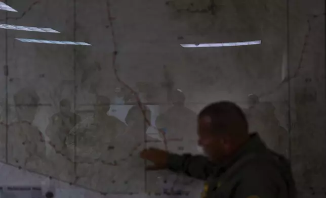U.S. military personnel are reflected on a map as they listen to Jose Luis Maheda during a briefing at the U.S. Border Patrol station in Nogales, Ariz., Tuesday, July 22, 2025. (AP Photo/Jae C. Hong)