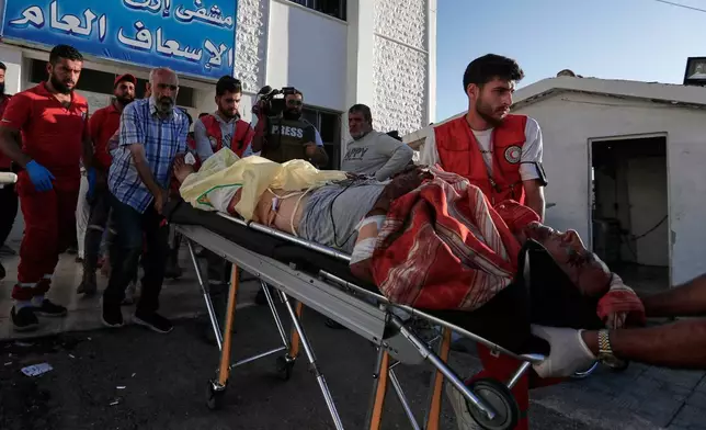 Syrian Red Crescent volunteers carry a man who was injured during clashes between Sunni Bedouin clans and Druze militias, at Ezraa hospital, southern Syria, Monday, July 14, 2025. (AP Photo/Omar Sanadiki)