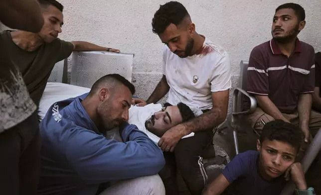 Mourners gather around the body of Ahmed Hajila who was killed by an Israeli airstrike that struck a school used as a shelter, in Shifa Hospital in Gaza City, on Thursday, July 3, 2025. (AP Photo/Jehad Alshrafi)