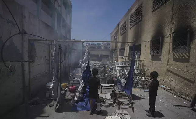 Palestinians children look at the destruction at a school used as a shelter after it was struck by an Israeli airstrike in Gaza City, on Thursday, July 3, 2025. (AP Photo/Jehad Alshrafi)