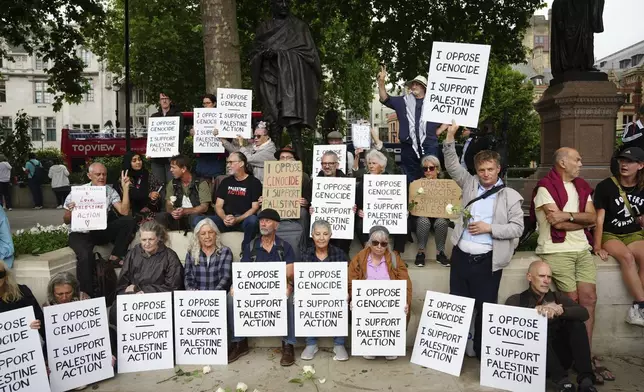People take part in a protest in support of 'Palestine Action', organised by the Defend Our Juries group, in front of the Mahatma Gandhi statue in Parliament Square in London, England, Saturday, July 5, 2025. (Jeff Moore/PA via AP)