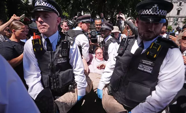Police officers remove a person after they took part in a protest in Parliament Square, to call for de-proscription of 'Palestine Action' after a ban against the organisation was announced, in London, Saturday July 12, 2025. (James Manning/PA via AP)