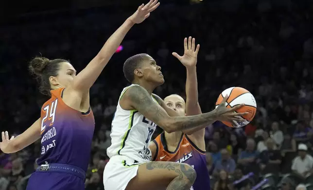 Minnesota Lynx guard Courtney Williams, center, drives past Phoenix Mercury forward Kathryn Westbeld (24) and Mercury guard Kitija Laksa, right, during the first half of a WNBA basketball game Wednesday, July 9, 2025, in Phoenix. (AP Photo/Ross D. Franklin)