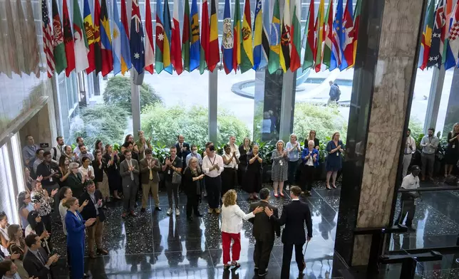 State Department employees applaud as their colleagues walk through the lobby of the State Department headquarters in the Harry S. Truman Building, Friday, July 11, 2025, in Washington. (AP Photo/Mark Schiefelbein).