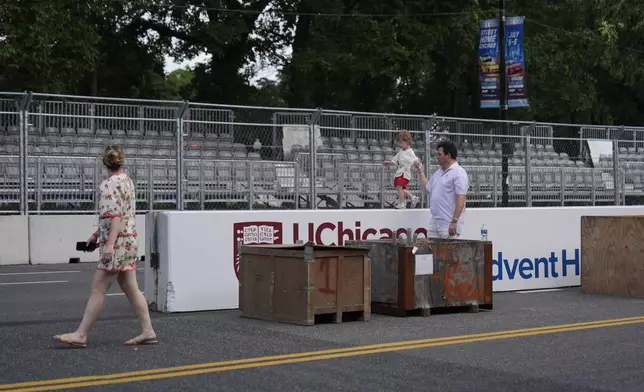 People walk by as construction of the street course continues ahead of the NASCAR auto racs, Friday, June 27, 2025, in downtown Chicago. (AP Photo/Erin Hooley)