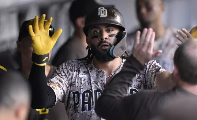San Diego Padres' Fernando Tatis Jr. is congratulated in the dugout after scoring a run on a single by Luis Arraez during the third inning of a baseball game against the Texas Rangers Sunday, July 6, 2025, in San Diego. (AP Photo/Orlando Ramirez)