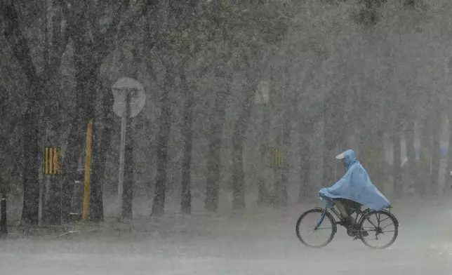 A man rides a bicycle during heavy rain in Beijing, China, Sunday, July 27, 2025. (AP Photo/Mahesh Kumar A.)