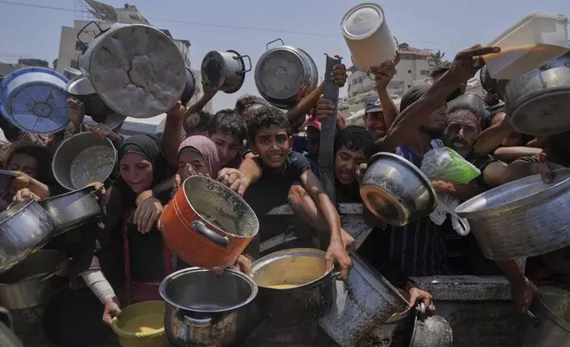 Palestinians struggle to get donated food at a community kitchen, in Gaza City, northern Gaza Strip, Saturday, July 26, 2025. (AP Photo/Abdel Kareem Hana)