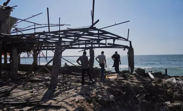 Palestinians walk in what was a cafe after it was damaged by an Israeli strike in Gaza City, Monday, June 30, 2025. (AP Photo/Jehad Alshrafi)
