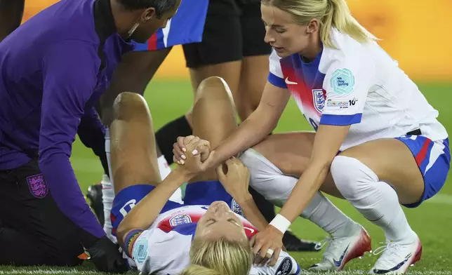 England's Chloe Kelly holds the hand of teammate Leah Williamson after she got injured during the Women's Euro 2025 quarterfinals soccer match between Sweden and England at Stadion Letzigrund in Zurich, Switzerland, Thursday, July 17, 2025. (AP Photo/Alessandra Tarantino)