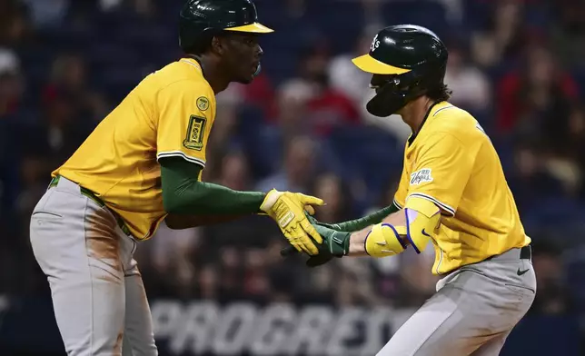 Athletics' Jacob Wilson, right, is congratulated by Denzel Clarke, left, after hitting a two-run home run off Cleveland Guardians relief pitcher Kolby Allard during the ninth inning of a baseball game, Saturday, July 19, 2025, in Cleveland. (AP Photo/David Dermer)