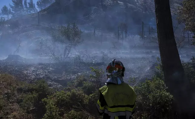 This photo provided by the fire brigade Pompiers13, shows a firefighter trying to extinguish a fire, near Marseille, southern France, Tuesday, July 8, 2025. (Pompiers13 via AP)