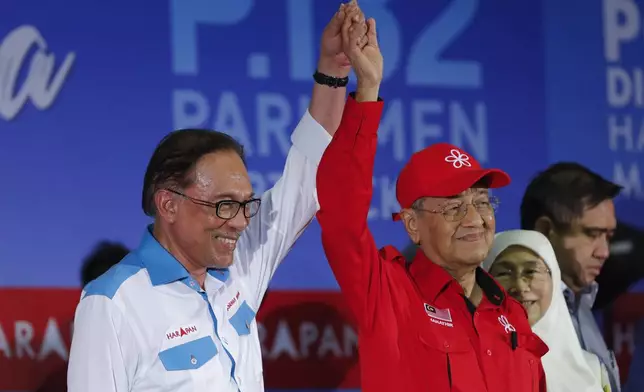 FILE- Then Malaysia's Prime Minister Mahathir Mohamad, right, raises the hand of Malaysia's reform icon Anwar Ibrahim during a rally in Port Dickson, Malaysia on Oct. 8, 2018. (AP Photo/Vincent Thian, File)