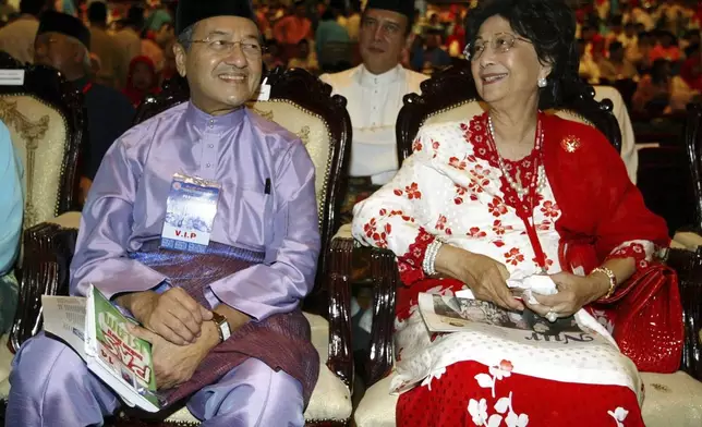 FILE - Former Malaysian Prime Minister Mahathir Mohamad, left, and his wife Siti Hasmah smile as they attend at the general assembly during United Malays National Organization (UMNO) 58th anniversary celebration in Kuala Lumpur, Sept. 23, 2004. (AP Photo/Vincent Thian,File)