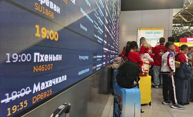 Passengers lineup to check-in for the first flight connecting Moscow and Pyongyang with a flight information board showing take-off time, at Moscow's Sheremetyevo International airport amidst the warming relations between Russia and North Korea outside Moscow, Russia, Sunday, July 27, 2025. (AP Photo)