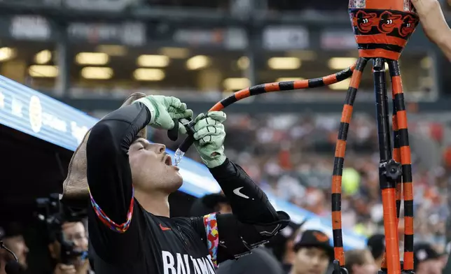 Baltimore Orioles' Alex Jackson drinks from the homer hose in the dugout after hitting a home run off Colorado Rockies pitcher Kyle Freeland during the second inning of a baseball game in Baltimore, Friday, July 25, 2025. (AP Photo/Terrance Williams)