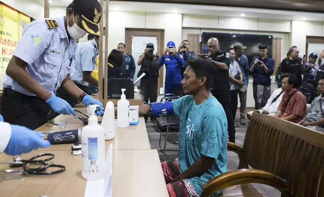 A paramedic gives health examination to a survivor rescued after a ferry sank, in Gilimanuk on Bali island, Indonesia, Thursday, July 3, 2025. (AP Photo/Firdia Lisnawati)