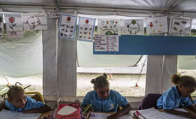Students work in a tented classroom at Sainte Jeanne D'Arc school in Port Vila, Vanuatu, Thursday, July 17, 2025. (AP Photo/Annika Hammerschlag)