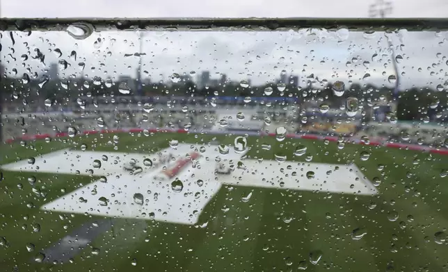 The covered pitch area is seen through glass speckled with droplets after rain delayed the start of play on day five of the second cricket test match between England and India at Edgbaston in Birmingham, England, Sunday, July 6, 2025. (AP Photo/Scott Heppell)