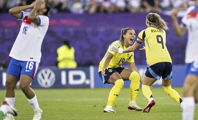Sweden's Kosovare Asllani, right, and Johanna Rytting Kaneryd, center, celebrate beside England's Jess Carter, left, after Asllani scored the opening goal during the Women's Euro 2025 quarterfinals soccer match between Sweden and England at Stadion Letzigrund in Zurich, Switzerland, Thursday, July 17, 2025. (Ennio Leanza/Keystone via AP)