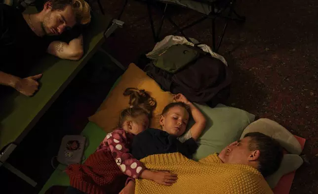 A family sleep on the platform of a metro station as they take cover during a Russian attack on Kyiv, Ukraine, on Thursday, July 10, 2025. (AP Photo/Evgeniy Maloletka)