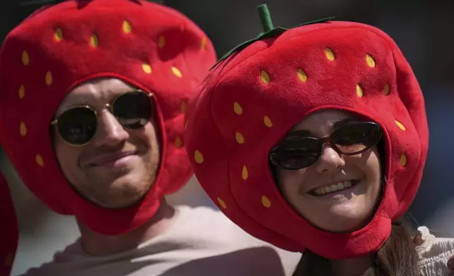 Tennis fans with strawberry hats watch tennis during the Wimbledon Tennis Championships in London, Monday, June 30, 2025. (AP Photo/Kin Cheung)
