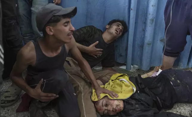 EDS NOTE: GRAPHIC CONTENT - Palestinians react beside their wounded sister, injured in an Israeli airstrike, as she brought to Shifa Hospital in Gaza City Saturday, July 12, 2025. (AP Photo/Jehad Alshrafi)